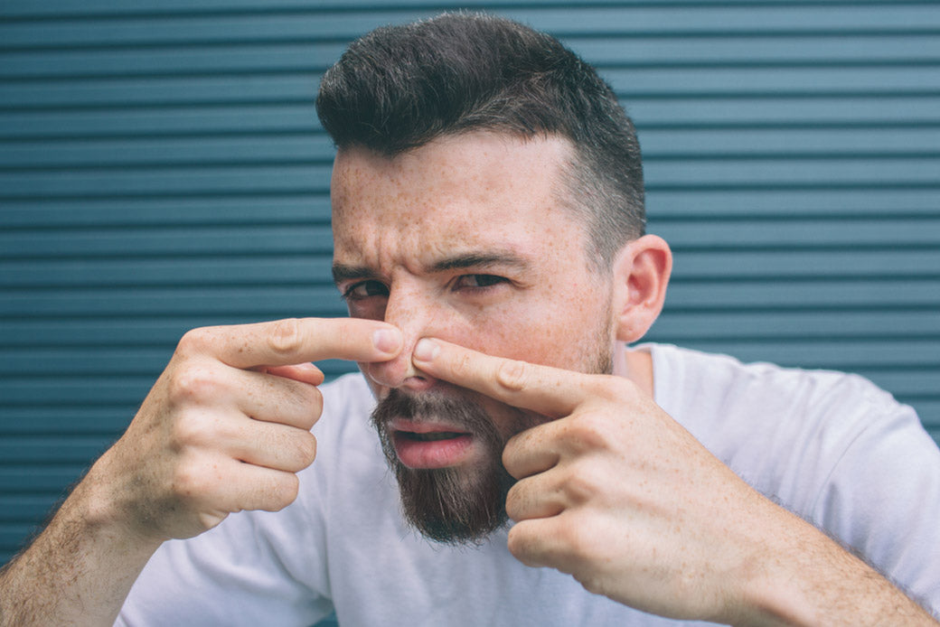 guy squeezing pimples on his nose