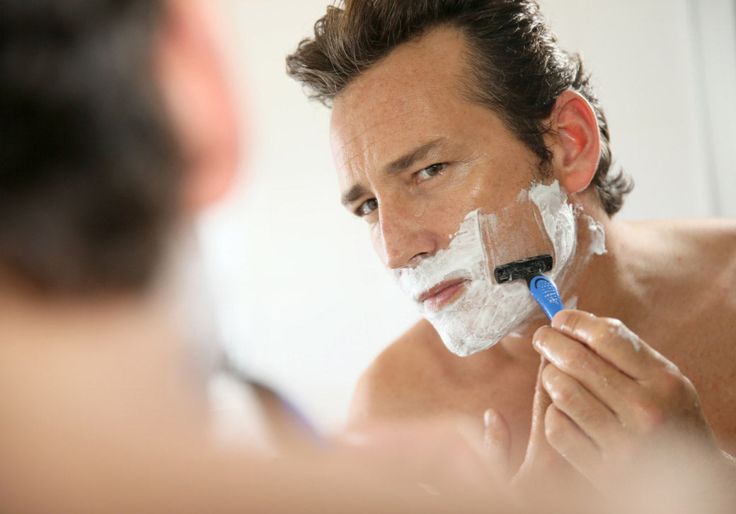 man shaving front of mirror