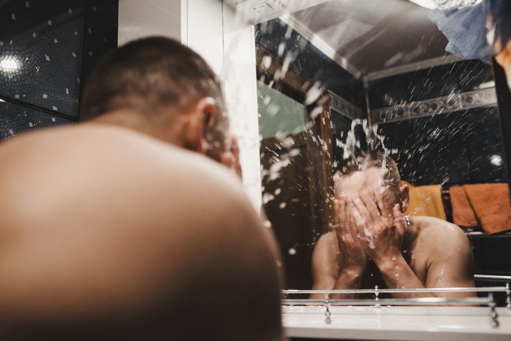 man splashing water on face